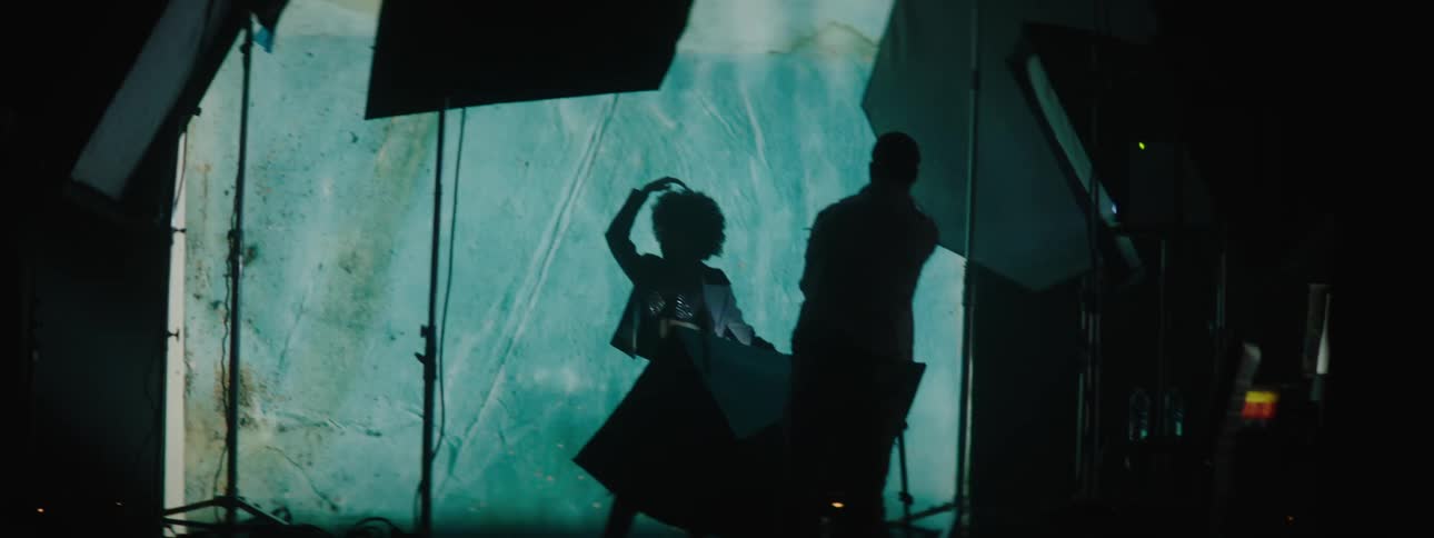 Photographer takes pictures of a model in front of a large projector in the background