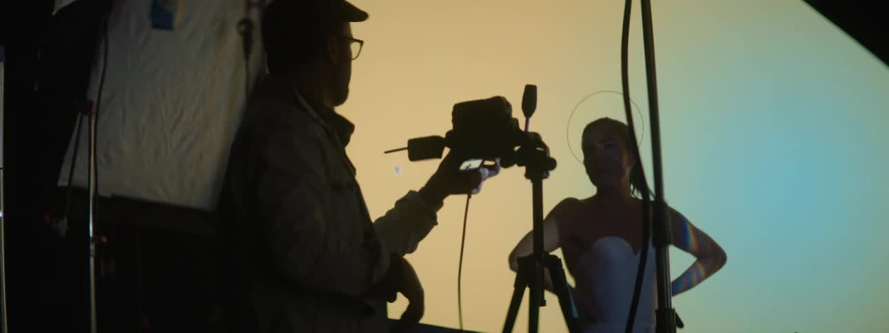 Photographer takes pictures of a model in front of a large projector in the background