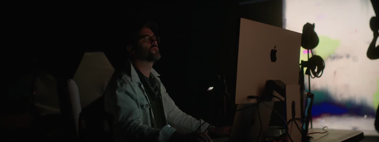 People working on a computer in a photography set with a large projector in the background