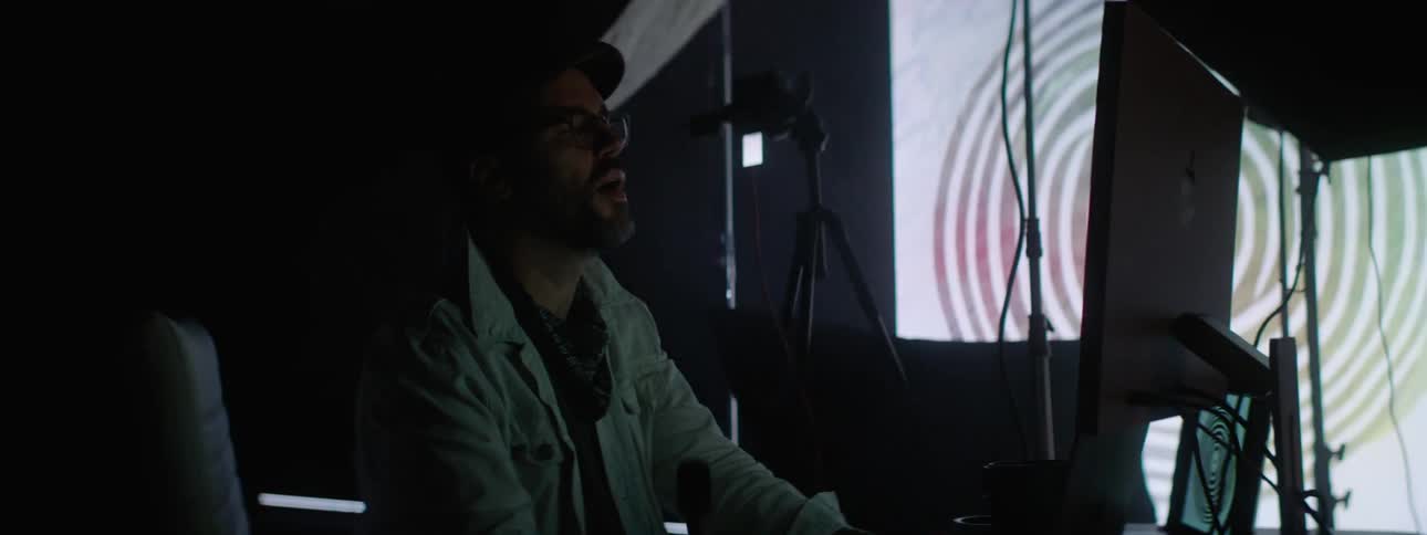 A clip of a man in a studio operating a computer