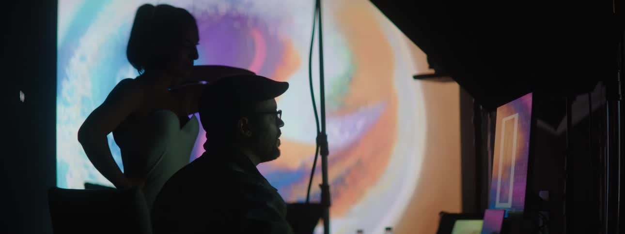 People working on a computer in a photography set with a large projector in the background