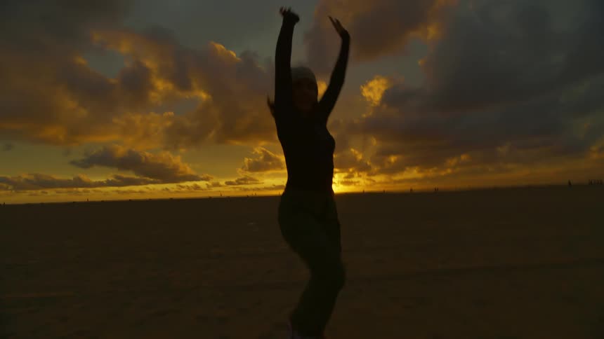 A young woman is running and having fun across a flat desert at sunset