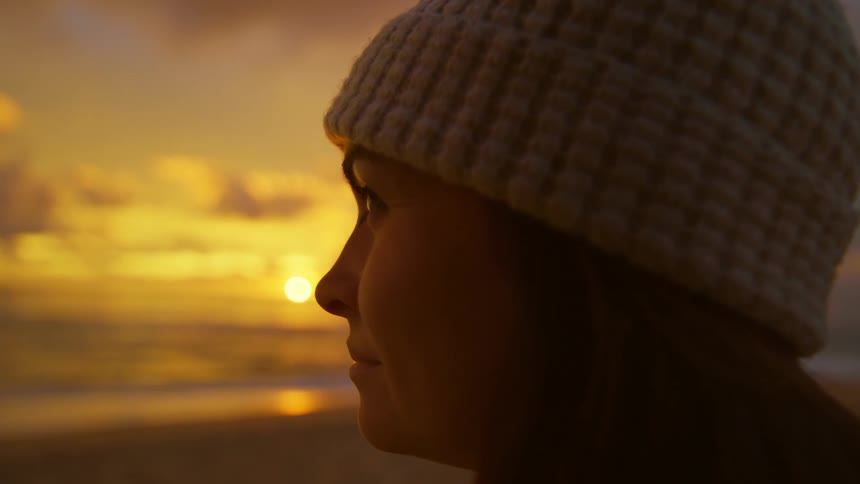 Close up of the face of a woman looking at the ocean at sunset