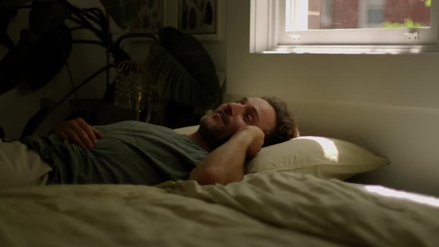 A man lying in bed talking on his cell phone