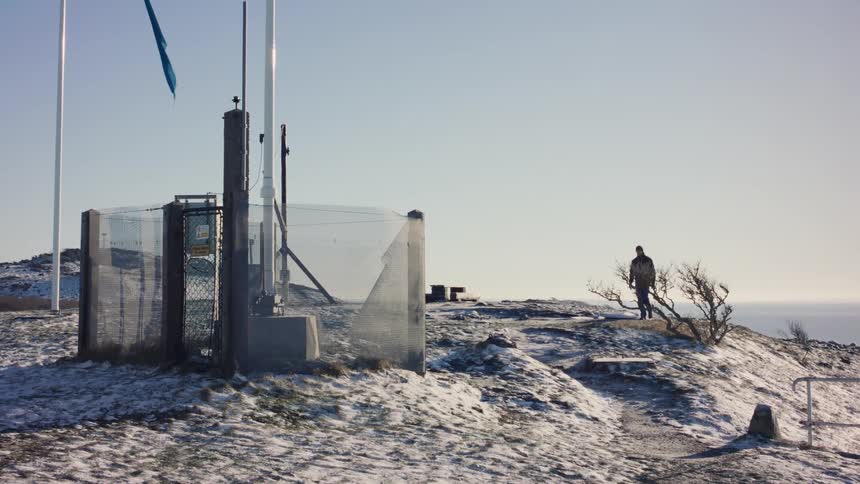 Man walking under a snowcovered hill towards a tower