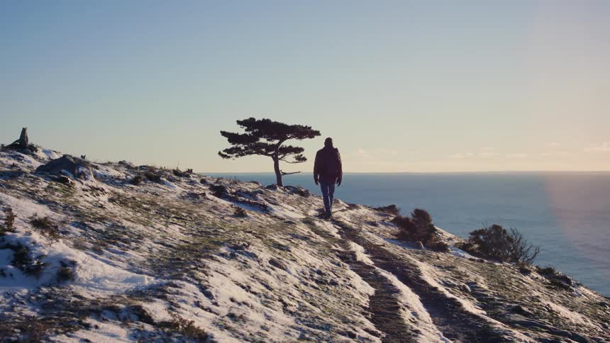 A person walking along the coastal hill on a sunny day