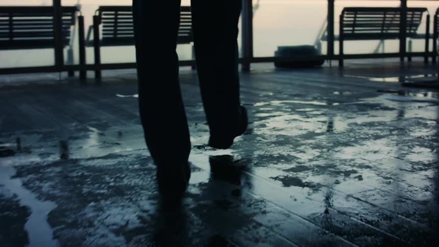 A person walking on wet ground during sunset