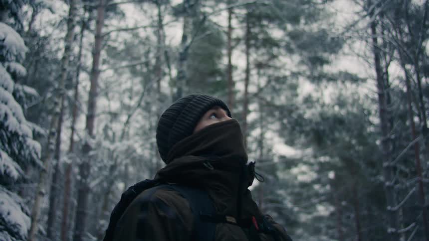 A boy admiring the forest trees covered in snow during winter