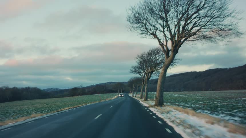 Driving on a tranquil road through the countryside at evening