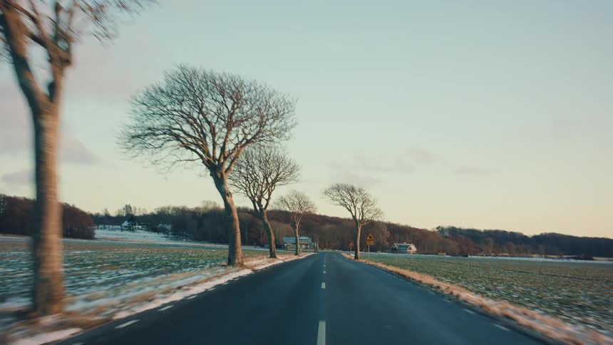 Highway passes snow covered fields and houses on a winter day