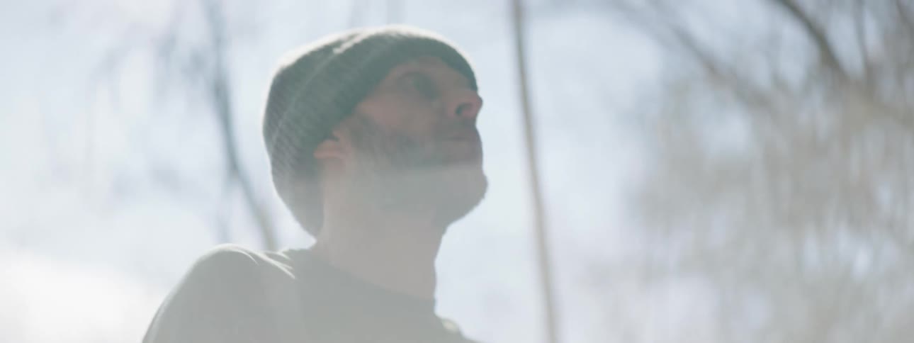 A man in the woods shakes off dust from his hands