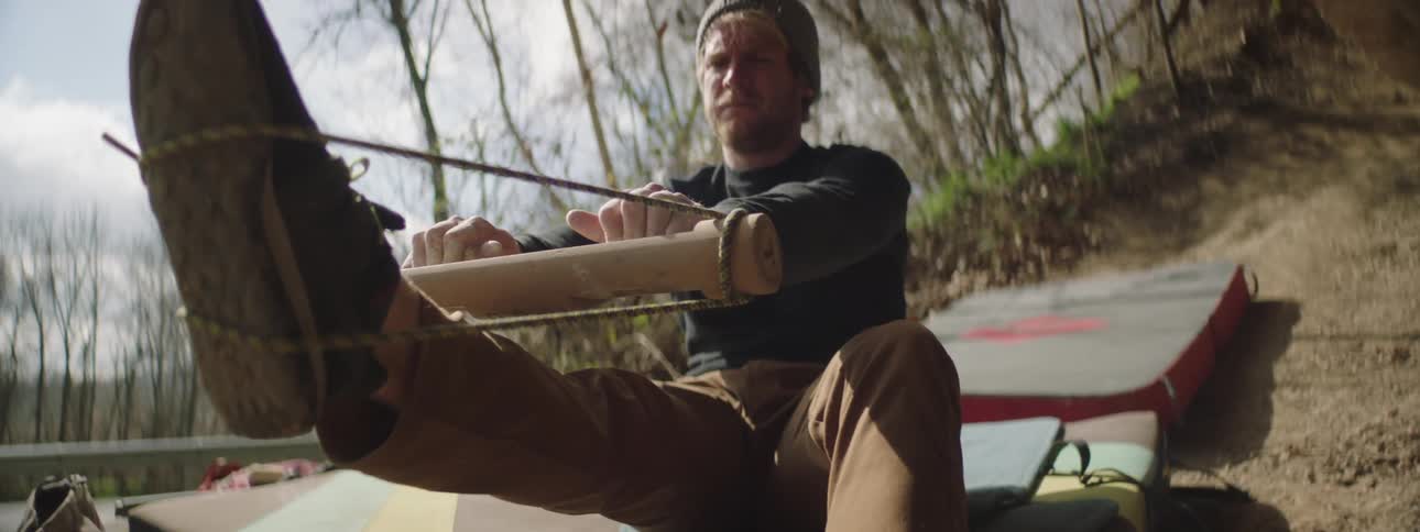 A man outdoors stretching while sitting down