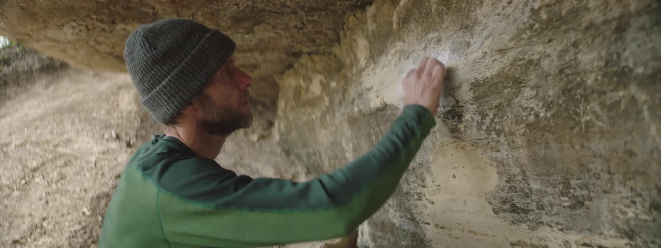 A man brushing a cave wall during the day