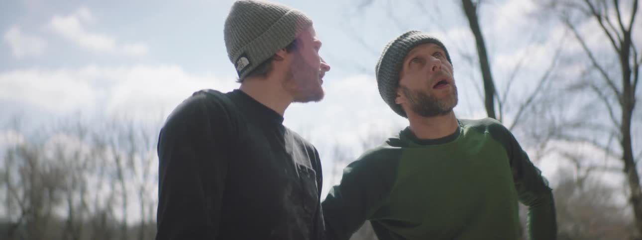 Two men look at something while discussing it pointing at it multiple times