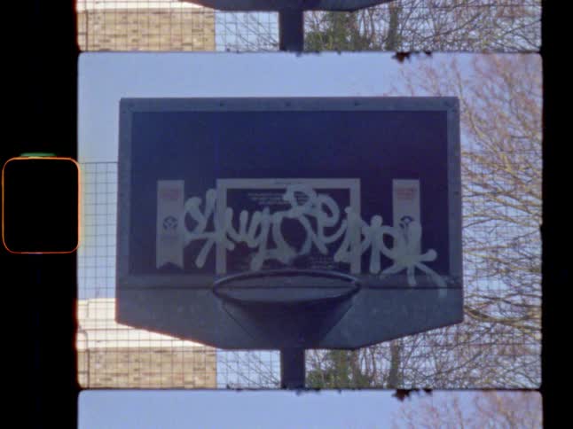 An old basketball hoop with graffiti covered backboard