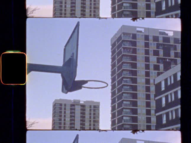 An outdoor basketball court surrounded by tower blocks