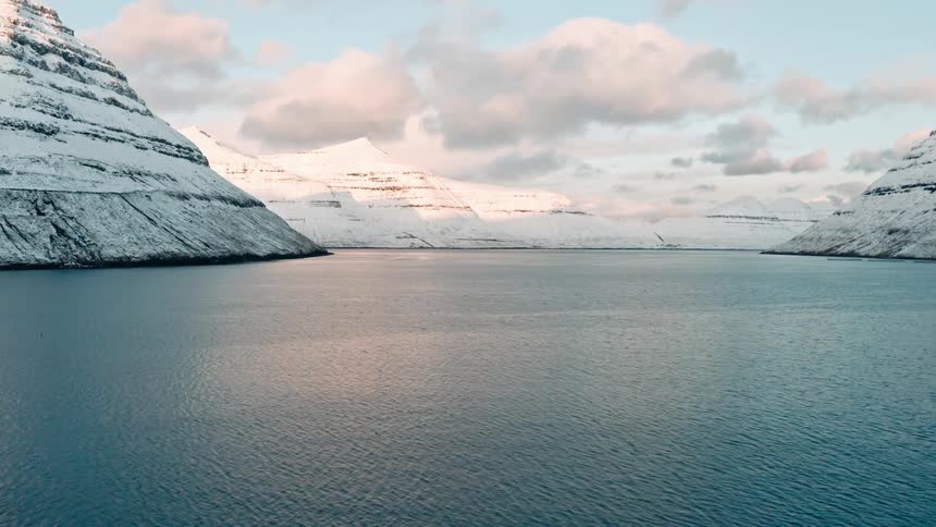 Coastal arctic waters reflect red tinted sunlight under red tinted clouds