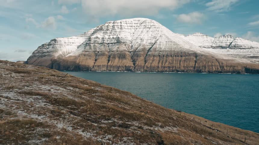 The ocean is near the snow covered mountains