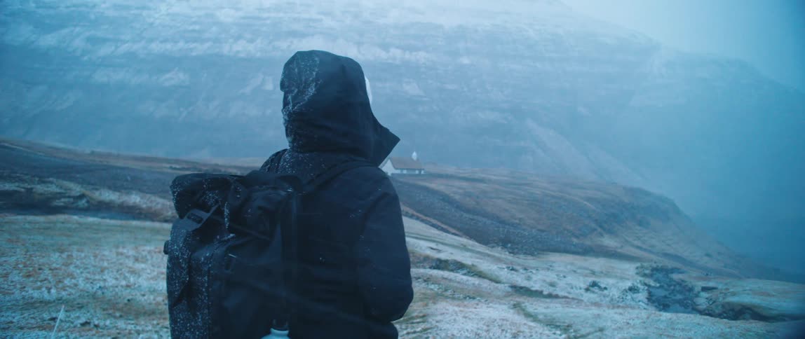 A woman stands before the mountain range