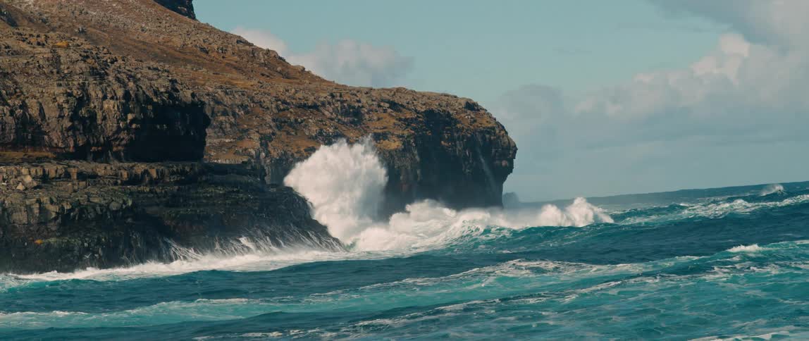 A large sea wave hitting a rock on the shore and making a splash