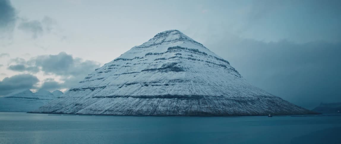 View of snowcapped mountain peaks by the sea under a morning sky