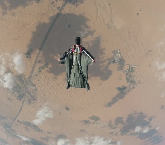 Aerial view of a skydiver wearing a wingsuit flying over the landscape