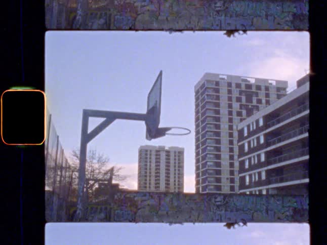 Basketball court with graffiti, surrounded by high rise tower blocks