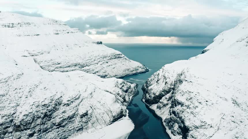 The mountains by the shore are covered with snow