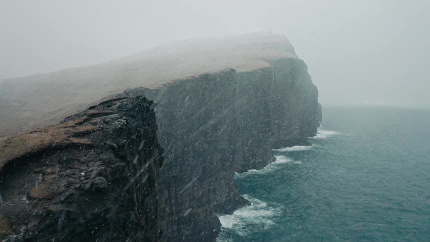 A cliff that leads straight into the ocean and its snowing