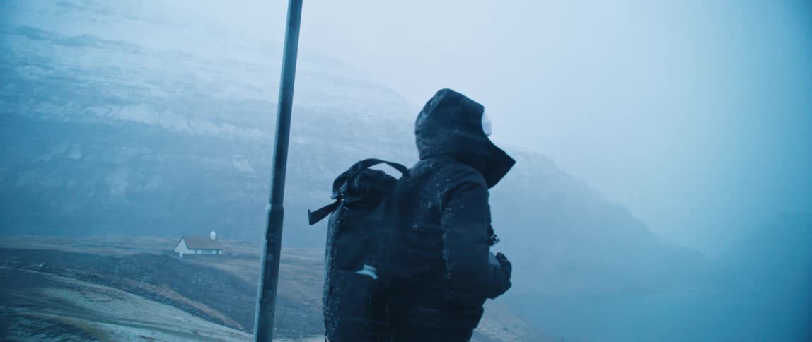 A backpacker hiking along a snowy road during a storm