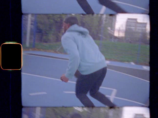 A man playing basketball outdoors, making a lay-up
