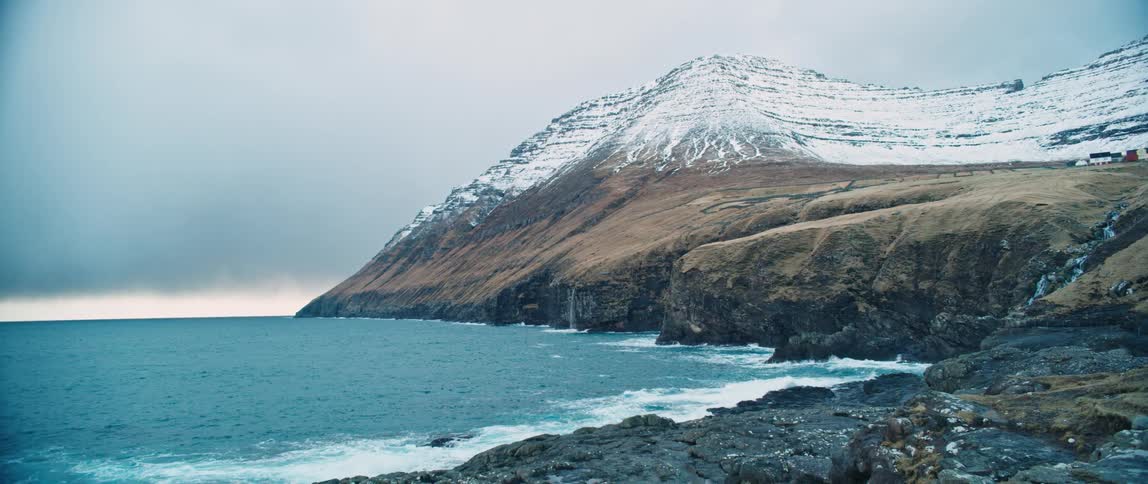 Coastal scene with snow covered mountains under an overcast sky