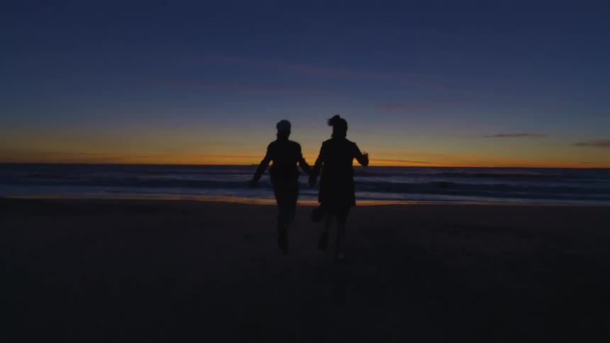 A clip of two people running towards the sea