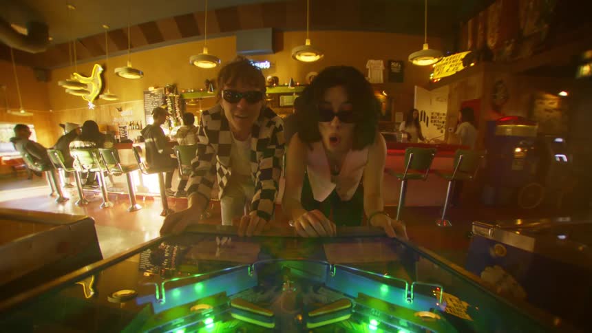 Two people are playing pinball in the bar