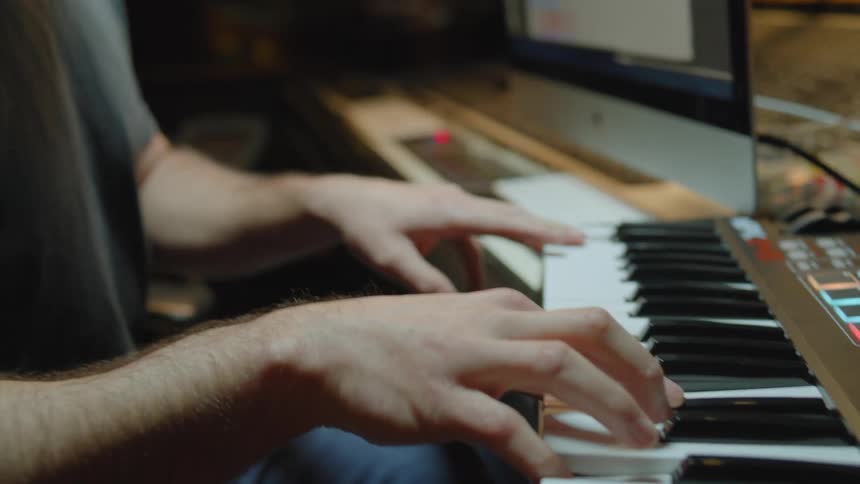 Man playing piano with a mixer in an indoor studio