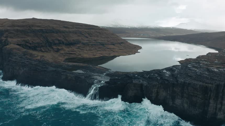 Aerial of sea waves breaking on mountain coast