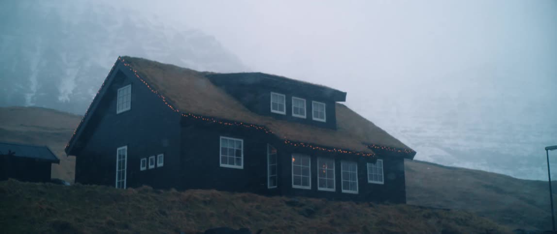 A cabin on a hill during a blizzard