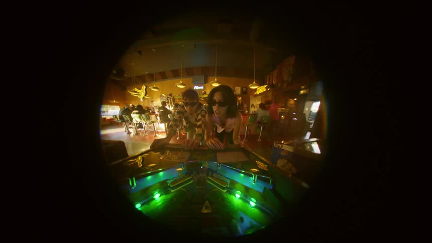 Young couple playing pinball together at a parlor