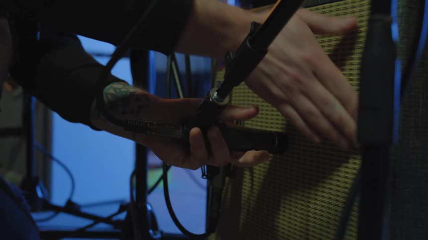 Man connects and places microphone in area lit by blue lighting during setup