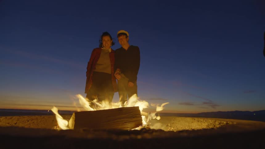 Two people stand by the campfire
