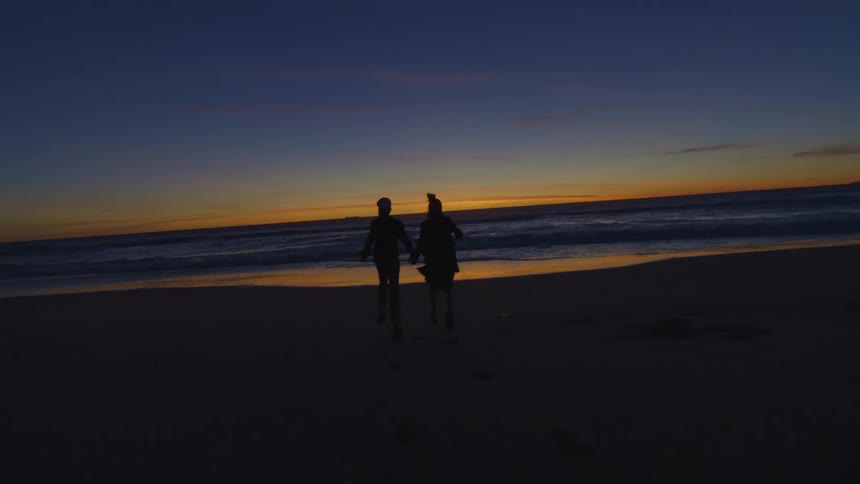 A clip of two friends holding hands and playing at the beach