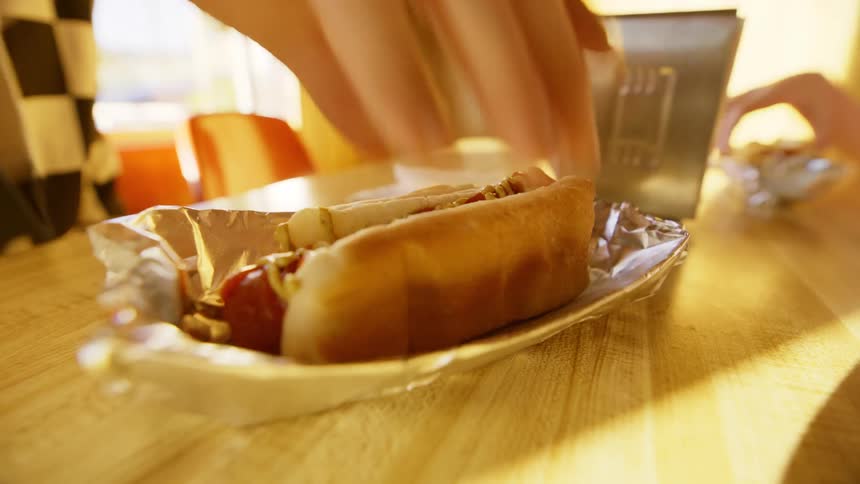 A person eats a hot dog in the restaurant