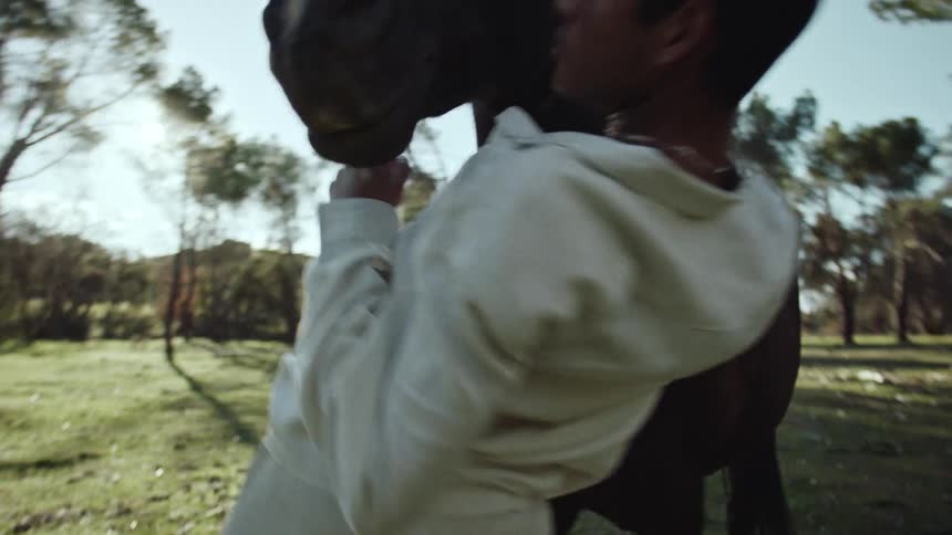 Man in a forest dancing in front of a black horse