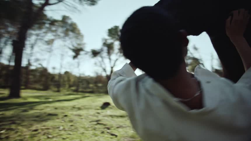 Black man dancing around a black horse in the green field