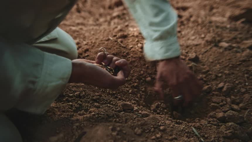 Latin man digging the soil with his hand