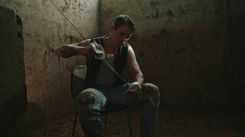 A sitting man cleaning a sword