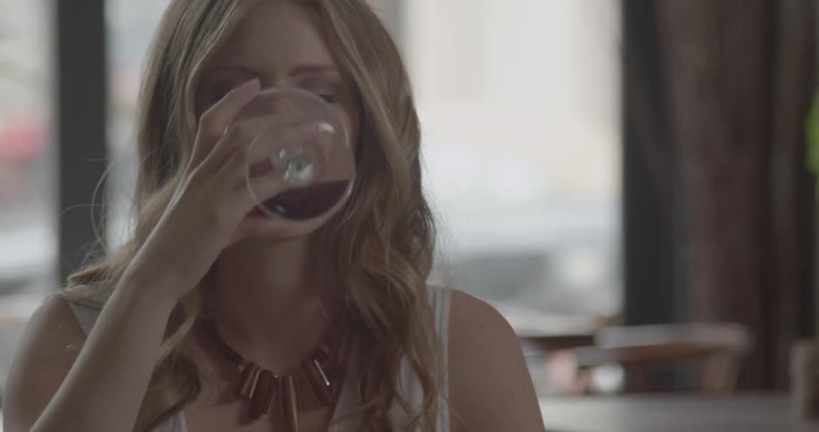 A woman is drinking wine and searching her purse