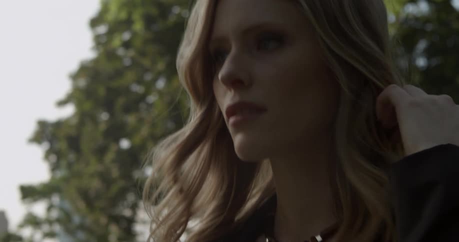 A woman walking in the woods adjust her hair