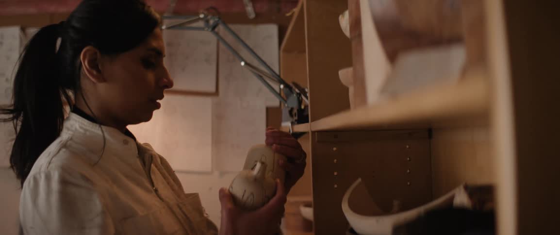 Woman takes small wooden sculptors off of shelf