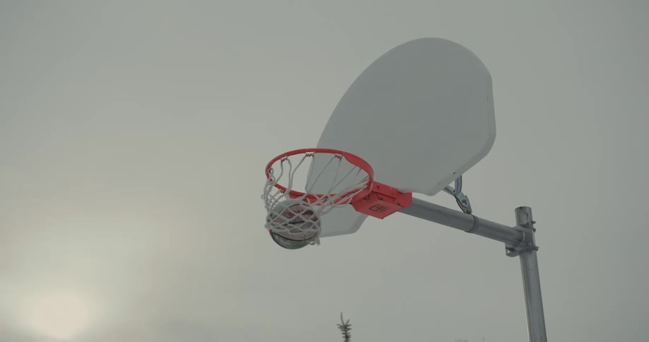 Slow motion of a basketball rebounding off a backboard and going through the net